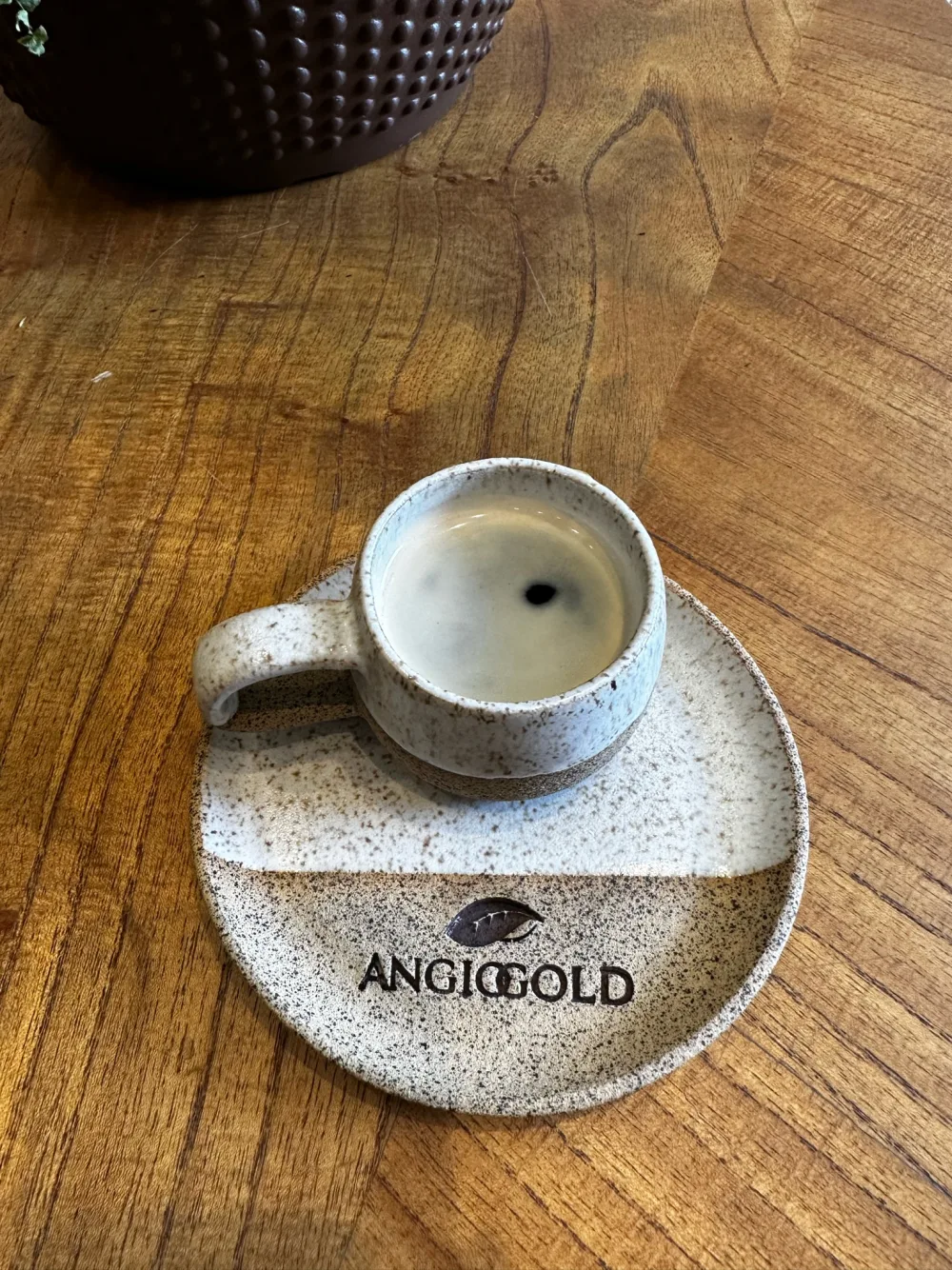 Xícara de café com a marca AngioGold, na sala de espera da clínica.